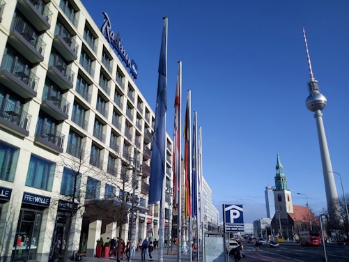 A city hall building with flags and clear blue sky in the background.