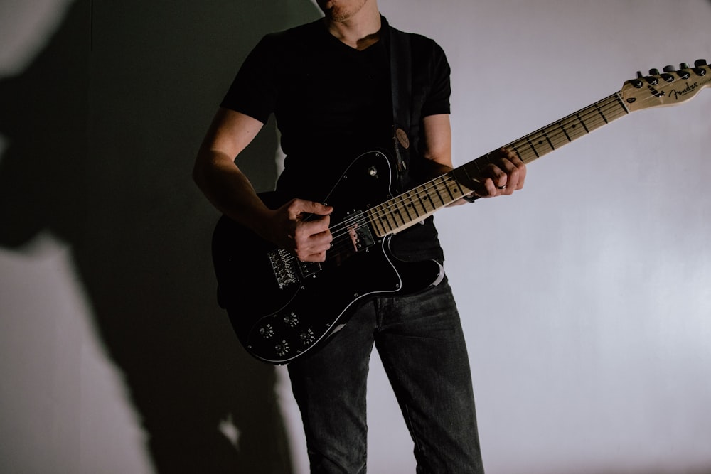 man wearing black shirt playing electric guitar