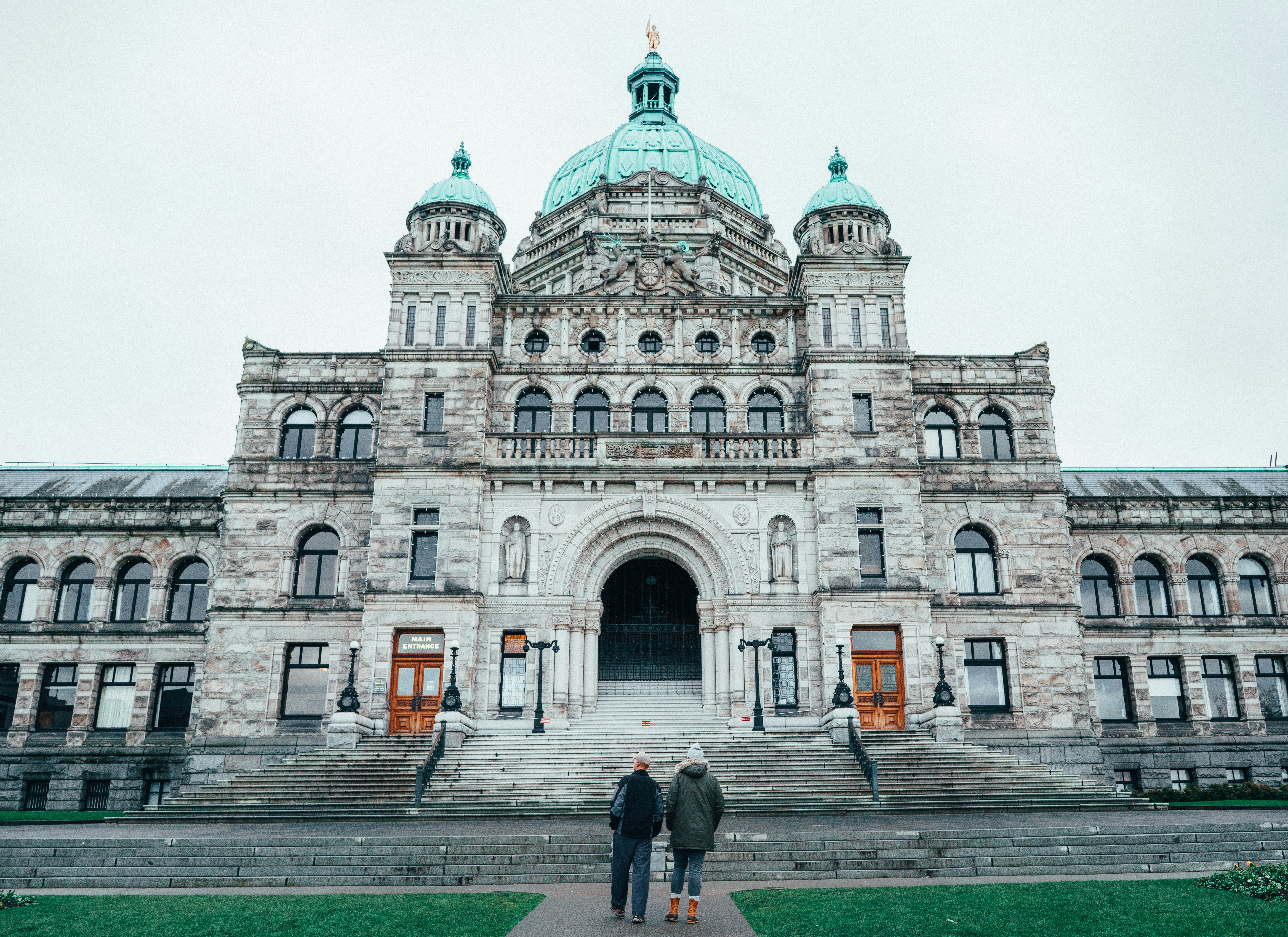 two people walking in front of gray building