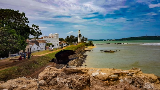 white building near body of water under cloudy sky in Galle Fort Sri Lanka