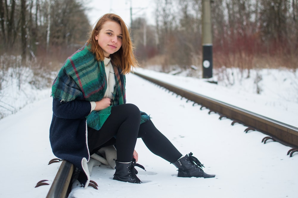 woman sitting on snow-covered train railway