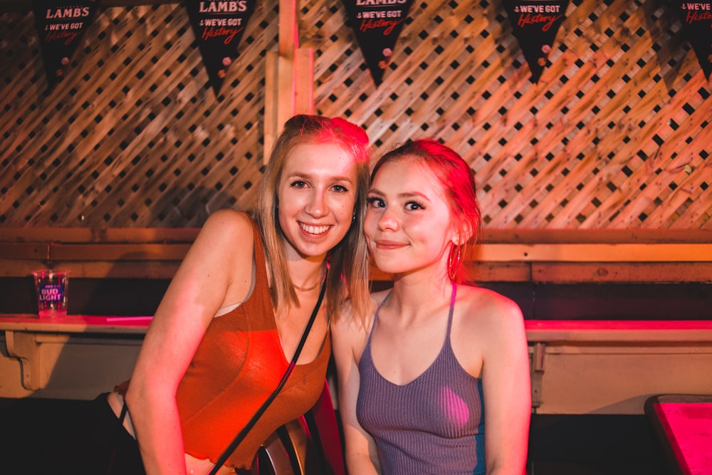 two women standing near brown wall