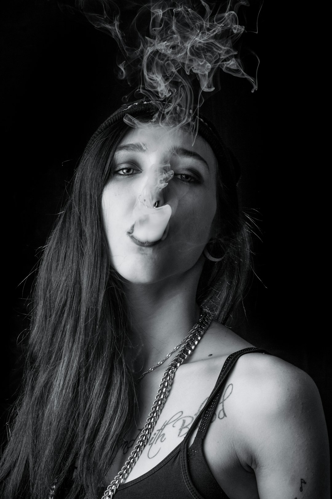 grayscale time-lapse photography of woman blowing smoke from her mouth