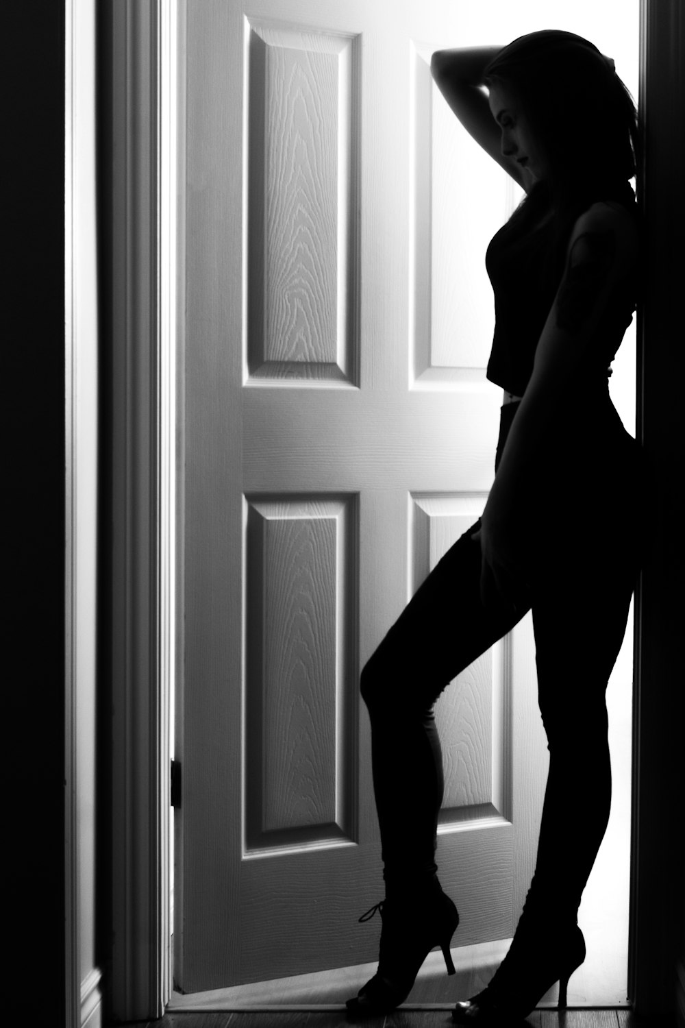 grayscale photography of woman standing on door