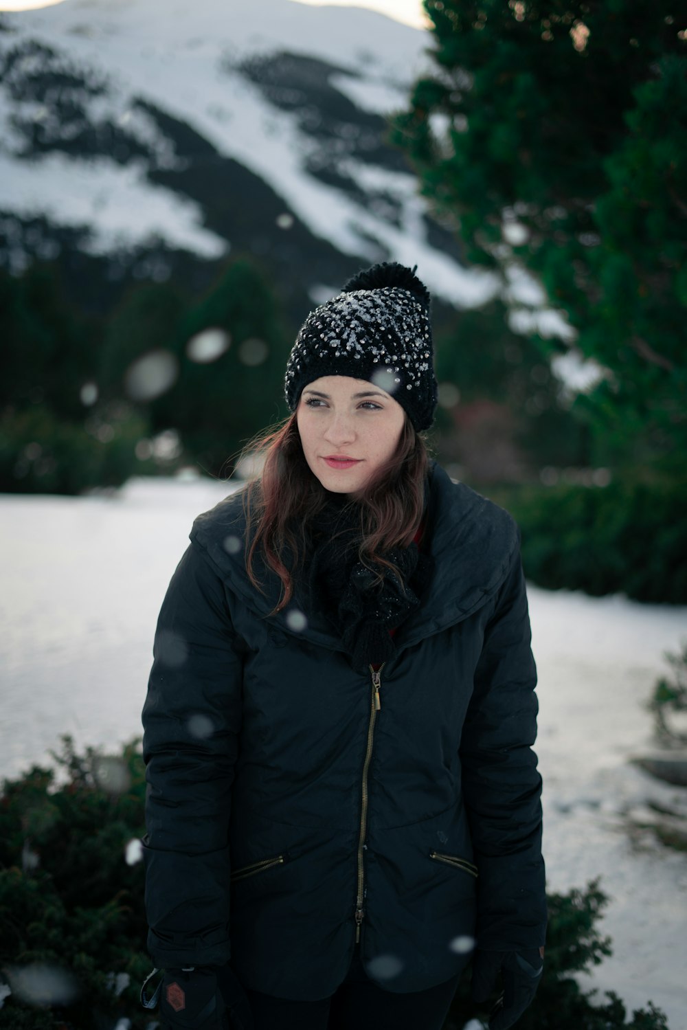 woman in black coat standing near trees during daytime