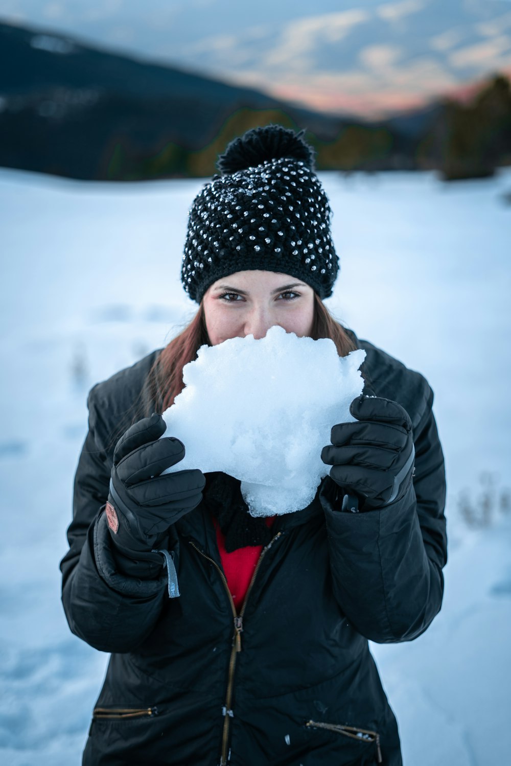 woman wearing black knit cap holding snow