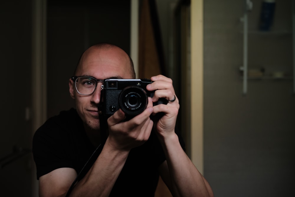 man taking picture using a black DSLR camera