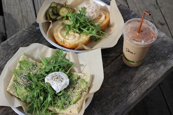 A beautifully arranged wooden tray with avocado toast, a berry smoothie, and a cup of herbal tea on a rustic table.