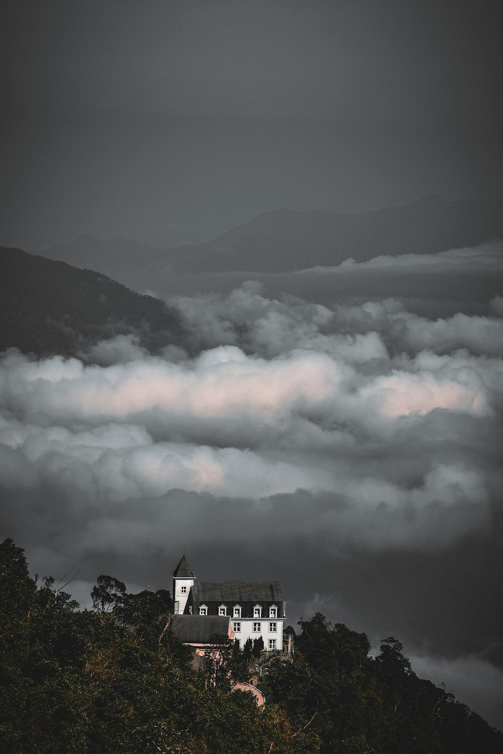 building on mountain near trees and clouds