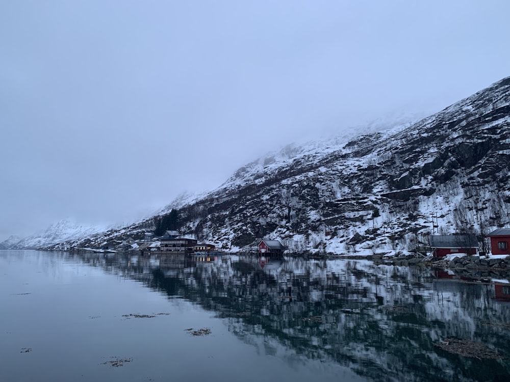 houses near body of water viewing mountain covered with snow during daytime