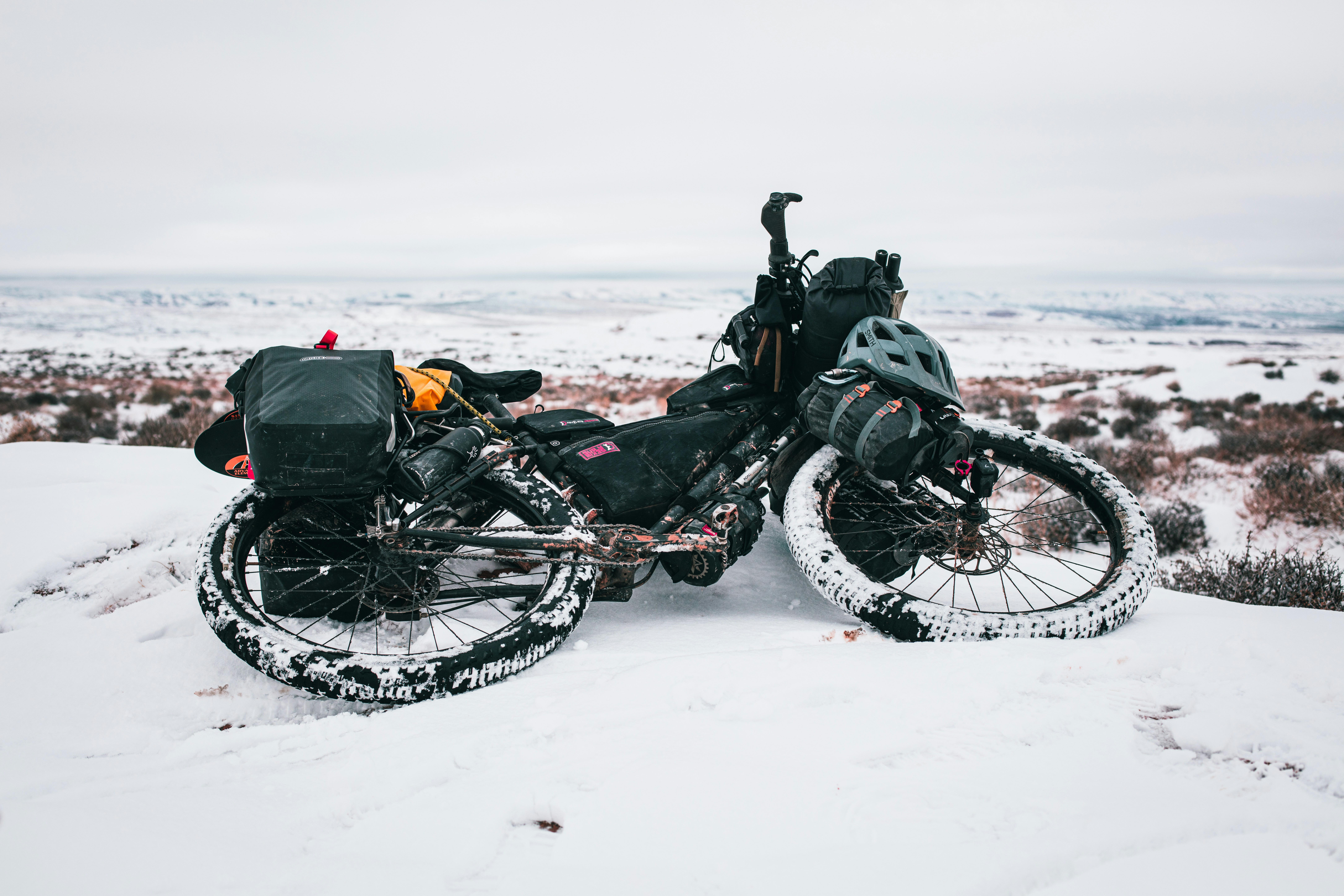 black bike on snowy road viewing body of water during daytime