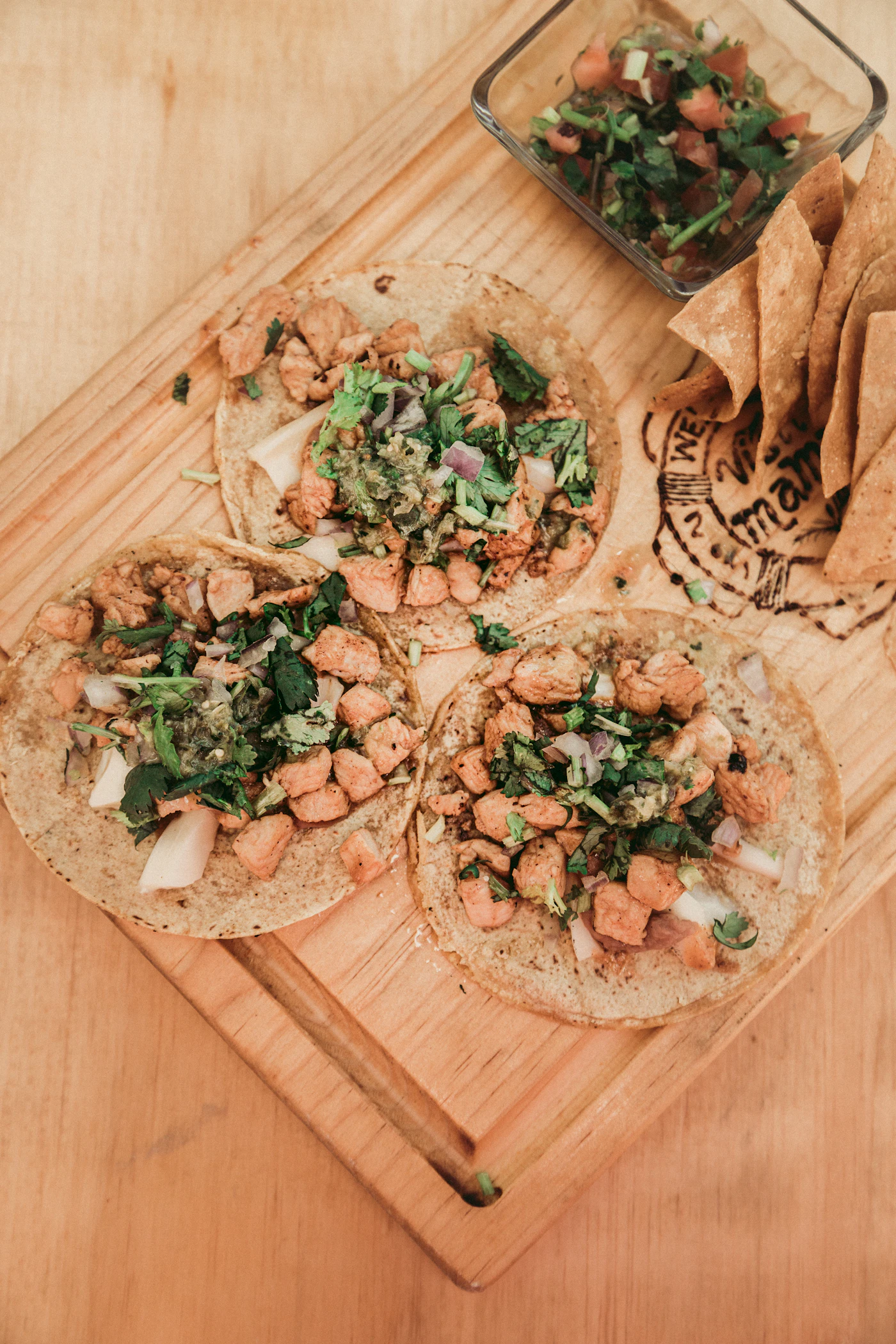A couple of street tacos on a wooden cutting board