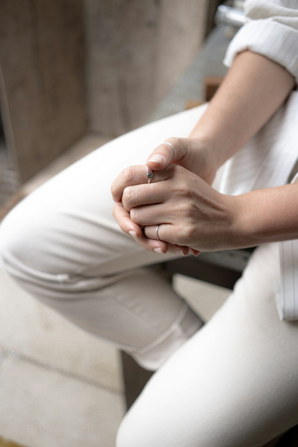 Una mujer sentada en una silla sosteniendo sus manos juntas