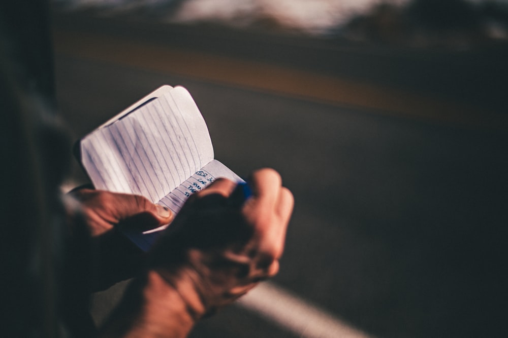selective focus photography of person holding ruled paper