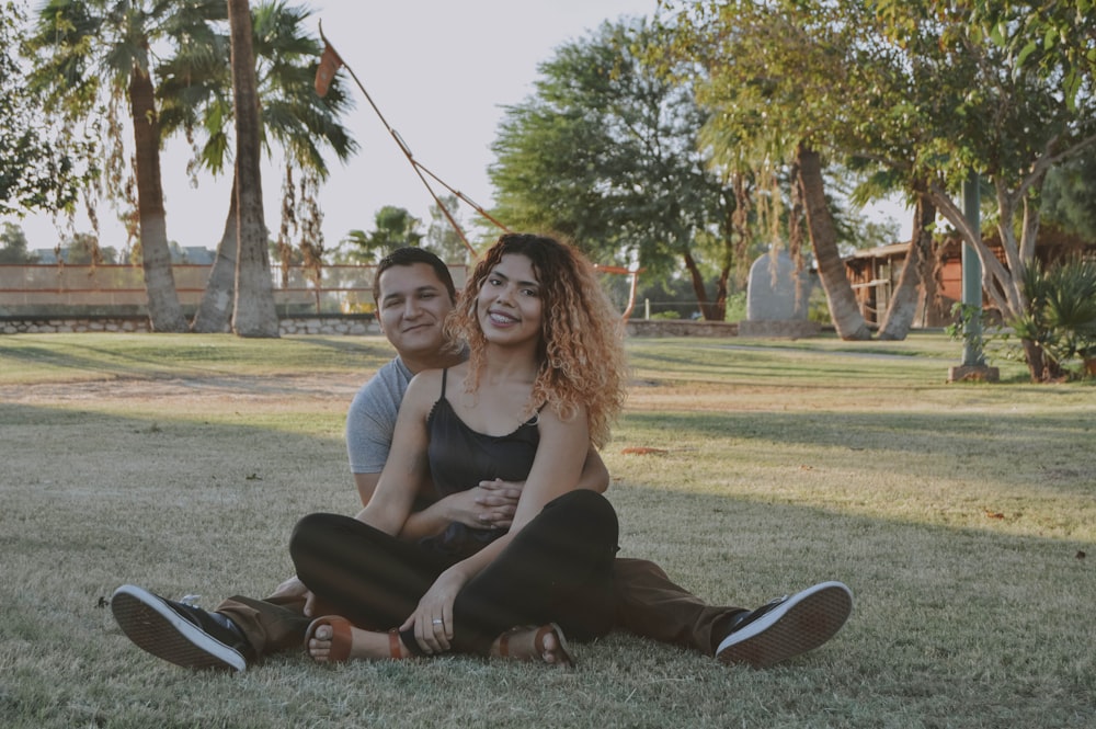 man and woman sitting on grass land