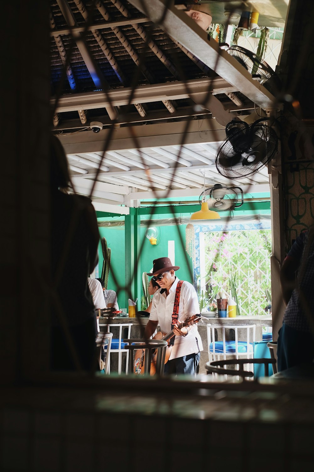 shallow focus photo of man wearing black hat playing guitar