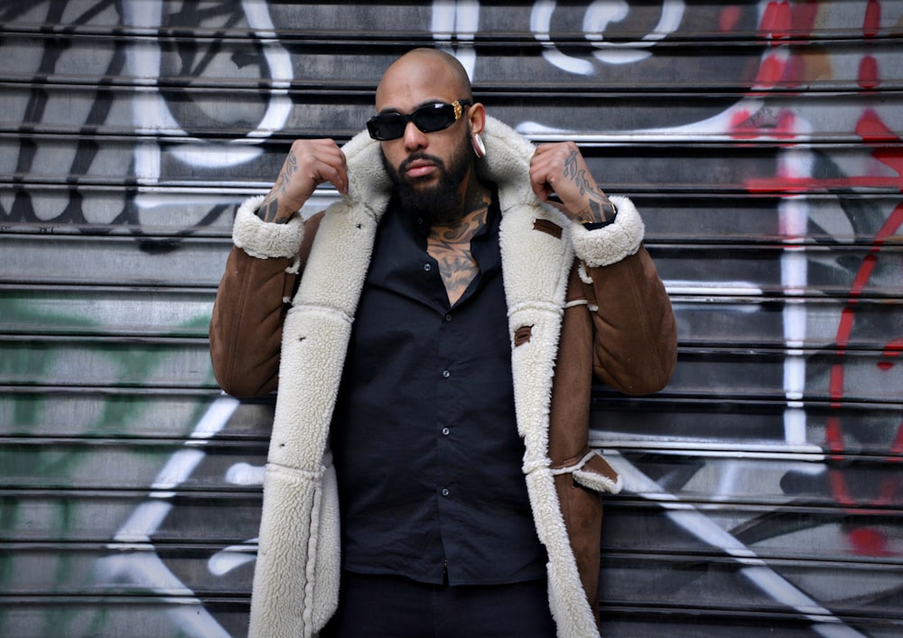 man in brown coat standing beside roller shutter