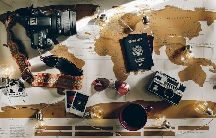 Image of a world map with travel objects on it, including sunglasses, passport and camera