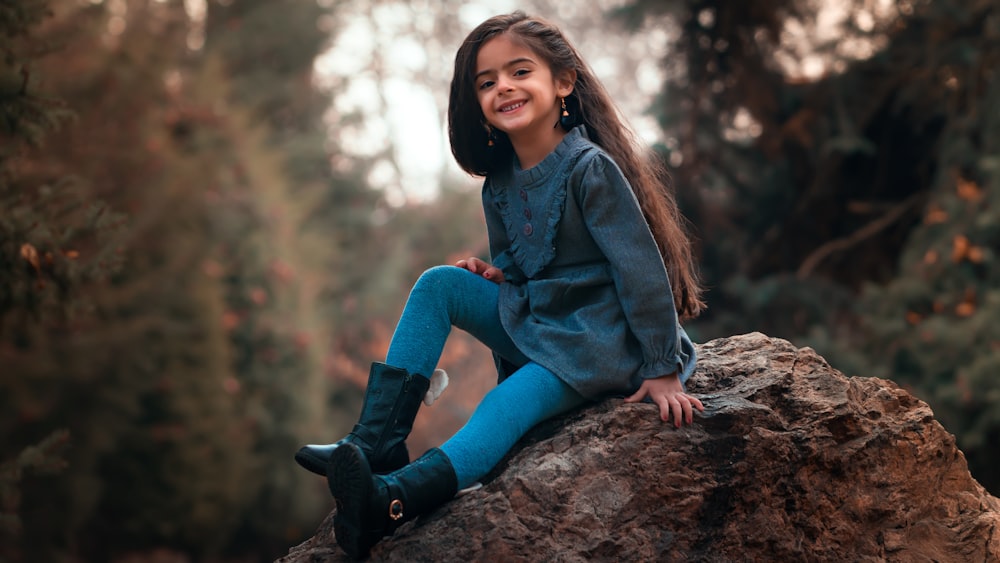 girl sitting on brown boulder