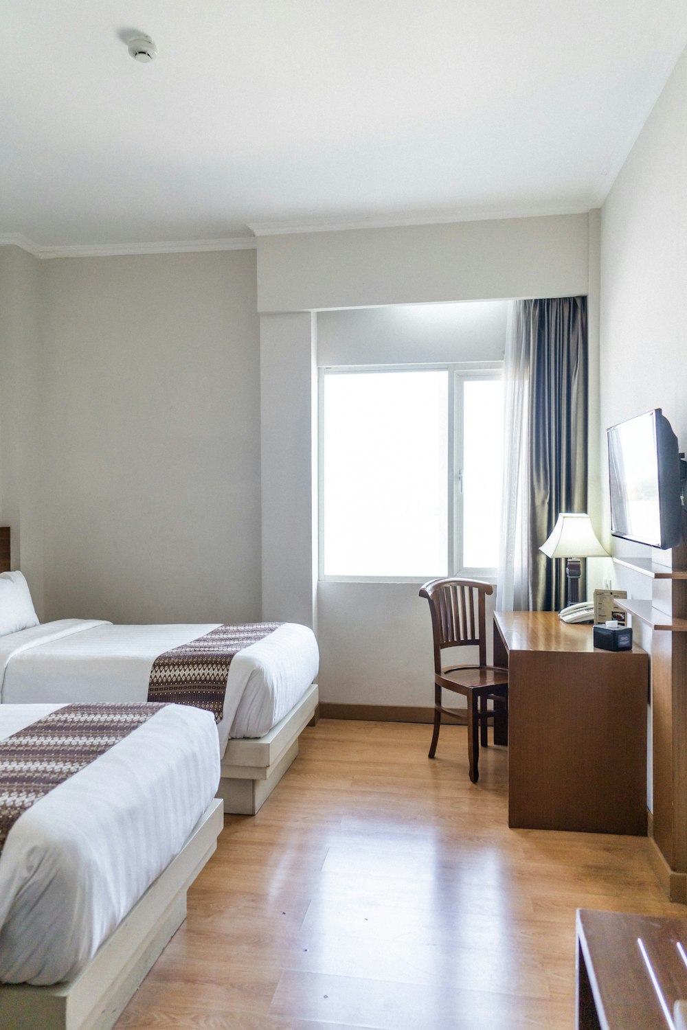 brown wooden table and chair near bed with comforter