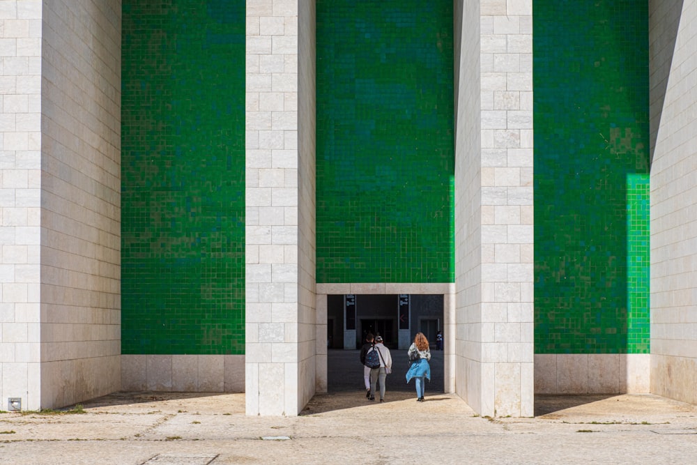 man and woman walking towards green and white building