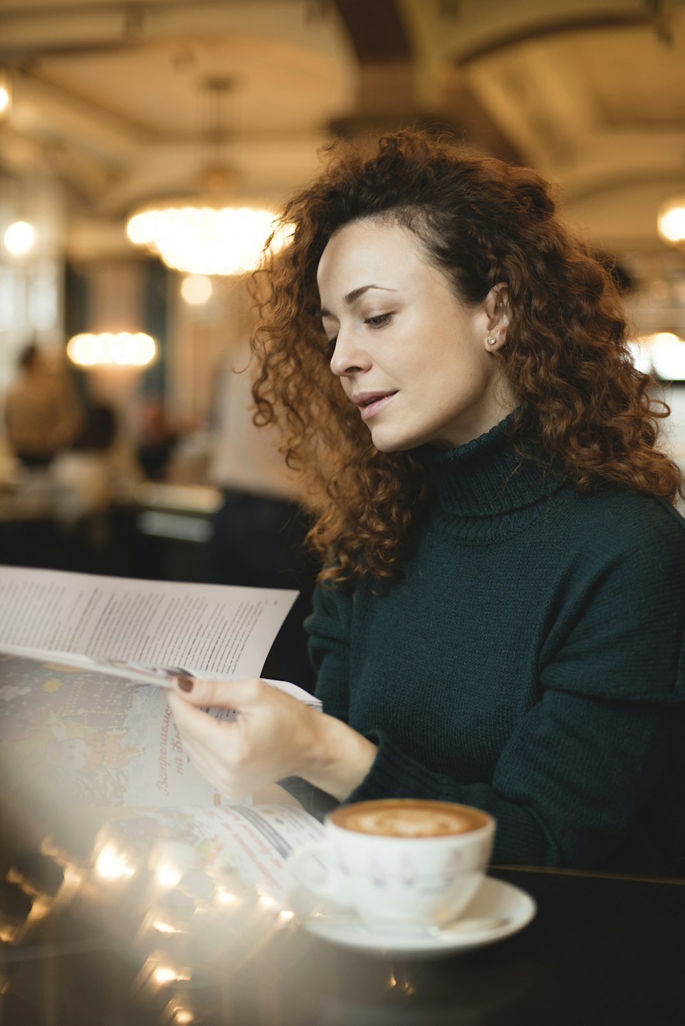 woman in teal sweater sitting beside table