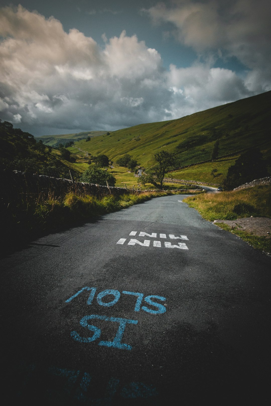 "Is Slow?" - A winding road in the Yorkshire Dales with marking on made by cyclists. 