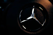 Close-up of a gold SSH monogram logo glowing softly against a deep navy background.