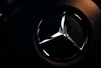 A close-up of a bronze diamond emblem embroidered on a minimalist black hoodie.