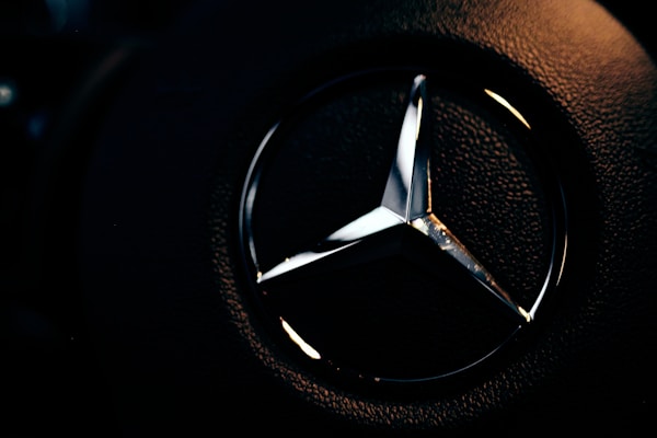 A close-up of a bronze diamond emblem embroidered on a minimalist black hoodie.