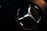 A close-up view of a metallic emblem on a textured black background, illuminated with subtle lighting that highlights its reflective surface.