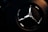 A close-up view of a metallic emblem on a textured black background, illuminated with subtle lighting that highlights its reflective surface.