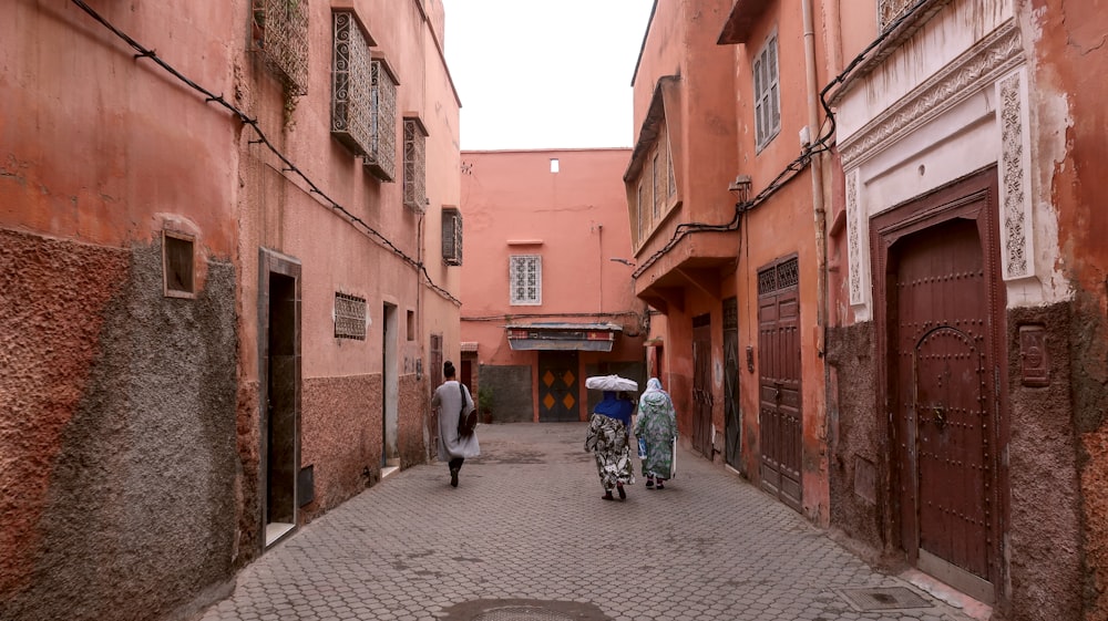 three person walking towards brown building