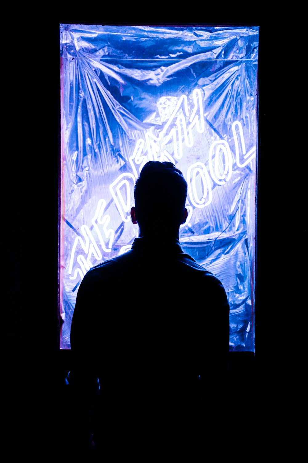 foto da silhueta do homem de frente para a sinalização neon