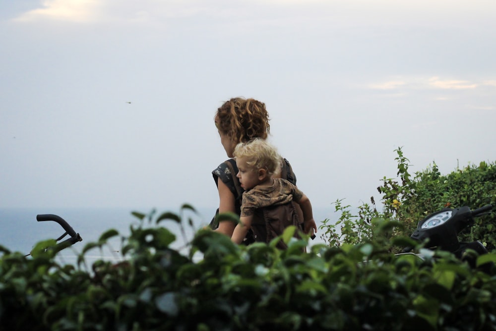 woman carrying child on back in plant field during daytime