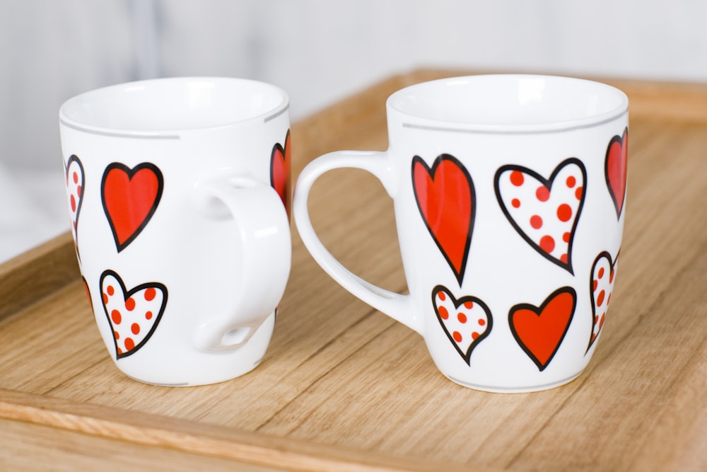 two white-and-red heart print ceramic mugs