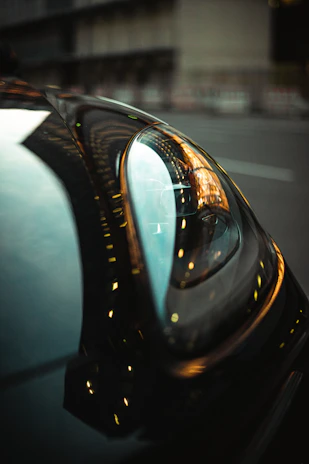 Close-up of a custom car's detailed grille and headlight with reflections of city lights.