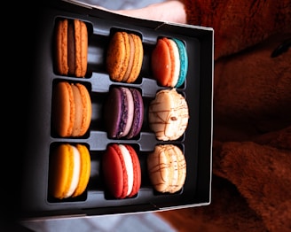 A vibrant box filled with jewel-toned macarons arranged neatly.