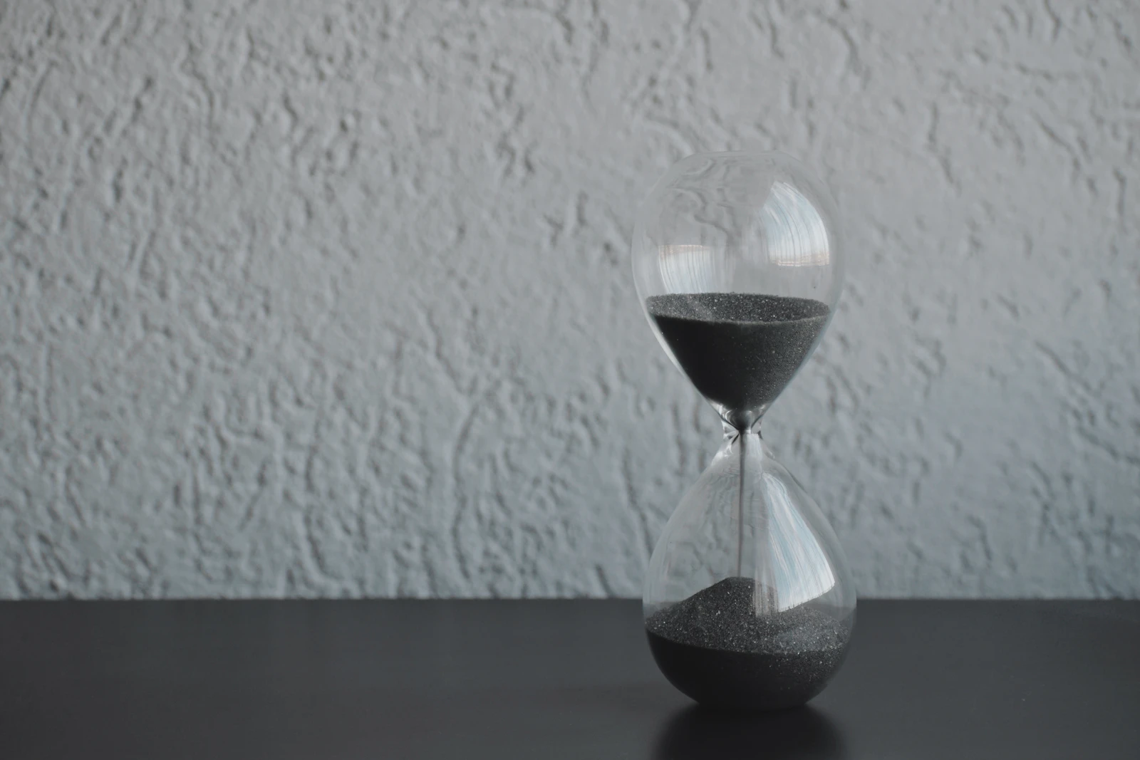 A clear hourglass with sand running through it, representing time
