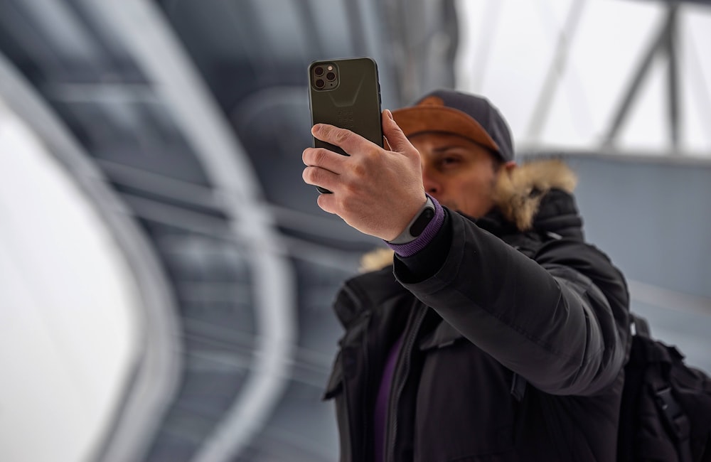 man in gray jacket holding iPhone 11 Pro Max
