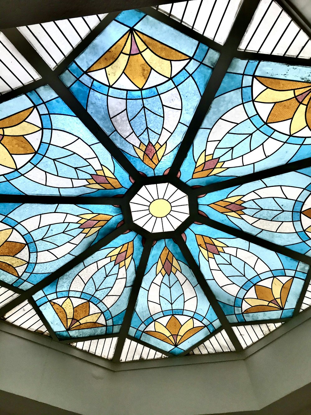 Photographie en contre-plongée d’un plafond en verre teinté bleu et jaune