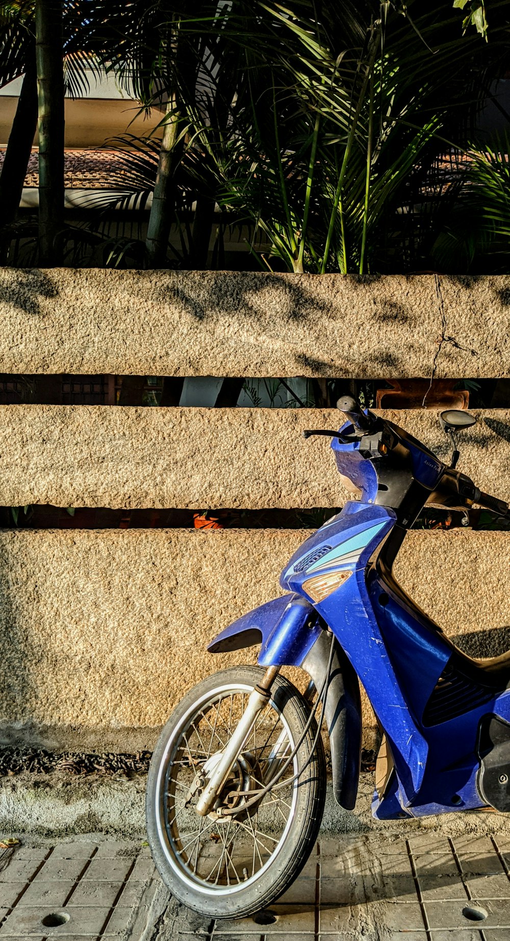 blue underbone motorcycle parked near fence