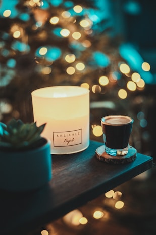 Close-up of a latte-scented candle glowing softly on a rustic wooden table.