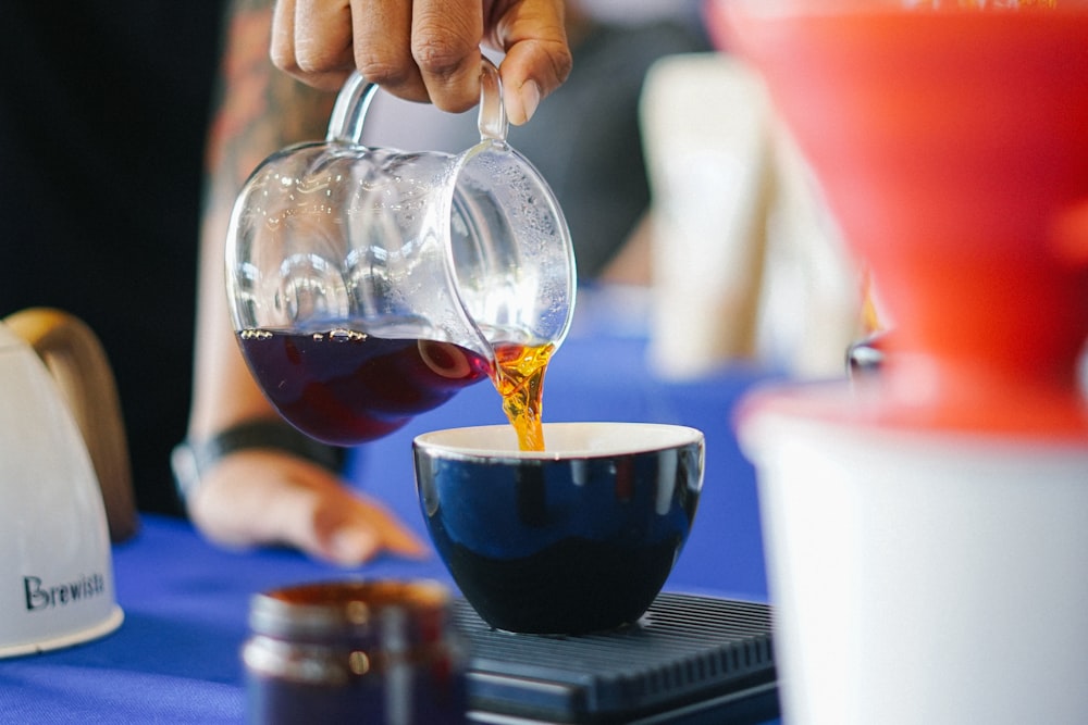 man pours hot coffee into cup