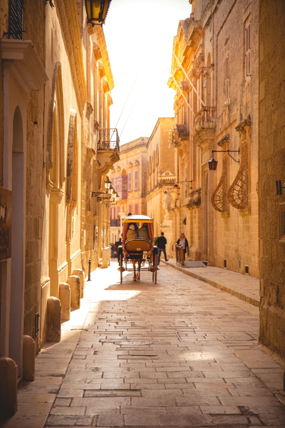 A horse-drawn karozzin carriage on a narrow honey-stone street in Mdina, Malta's Silent City