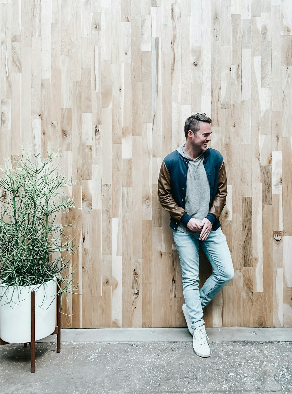 man leaning on brown plank wall facing right
