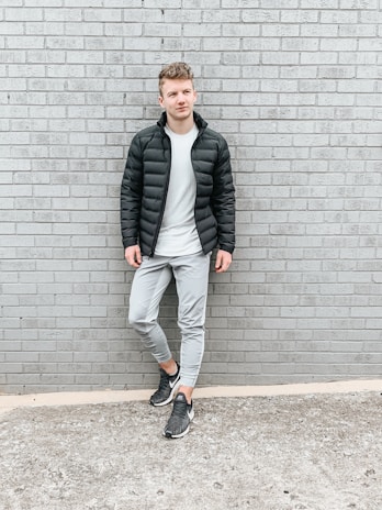 A clean, minimalist streetwear outfit displayed on a simple urban backdrop.