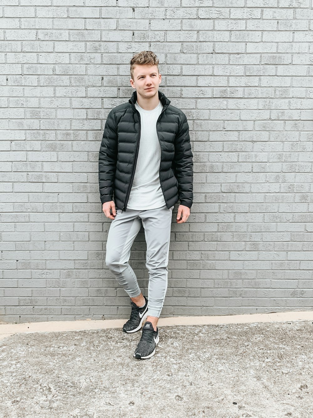 man in black jacket standing beside wall