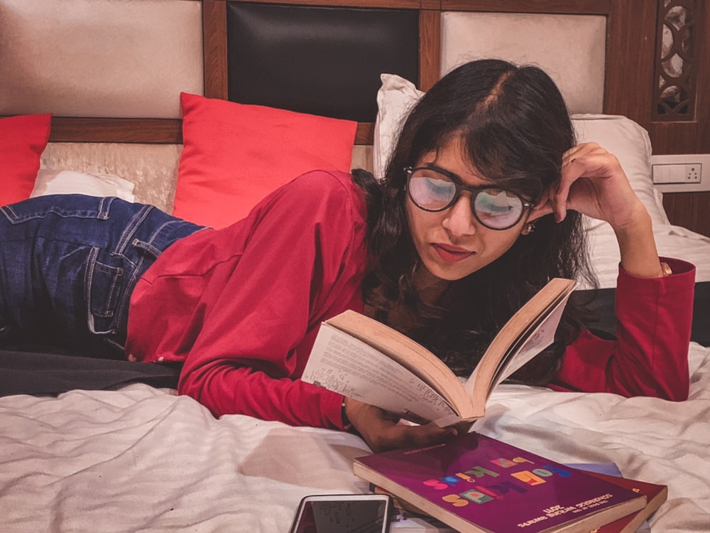 woman lying down on bed reading book