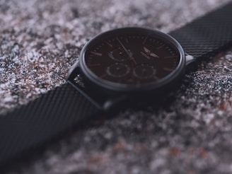 Close-up of a sleek black and yellow wristwatch resting on a textured surface.